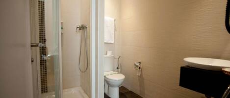 Une salle de bain avec une douche à parois de verre, des toilettes et un lavabo avec un meuble noir.