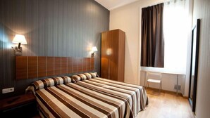 Une chambre d’hôtel avec un grand lit, un bureau et une armoire.