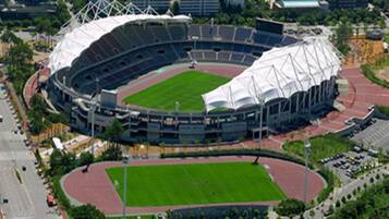 A stadium with a large central field and multiple seating tiers.