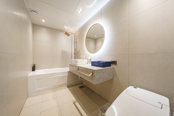A modern bathroom with a bathtub, a sink, a mirror, and a toilet. - Hotel Millennium (Goyang)