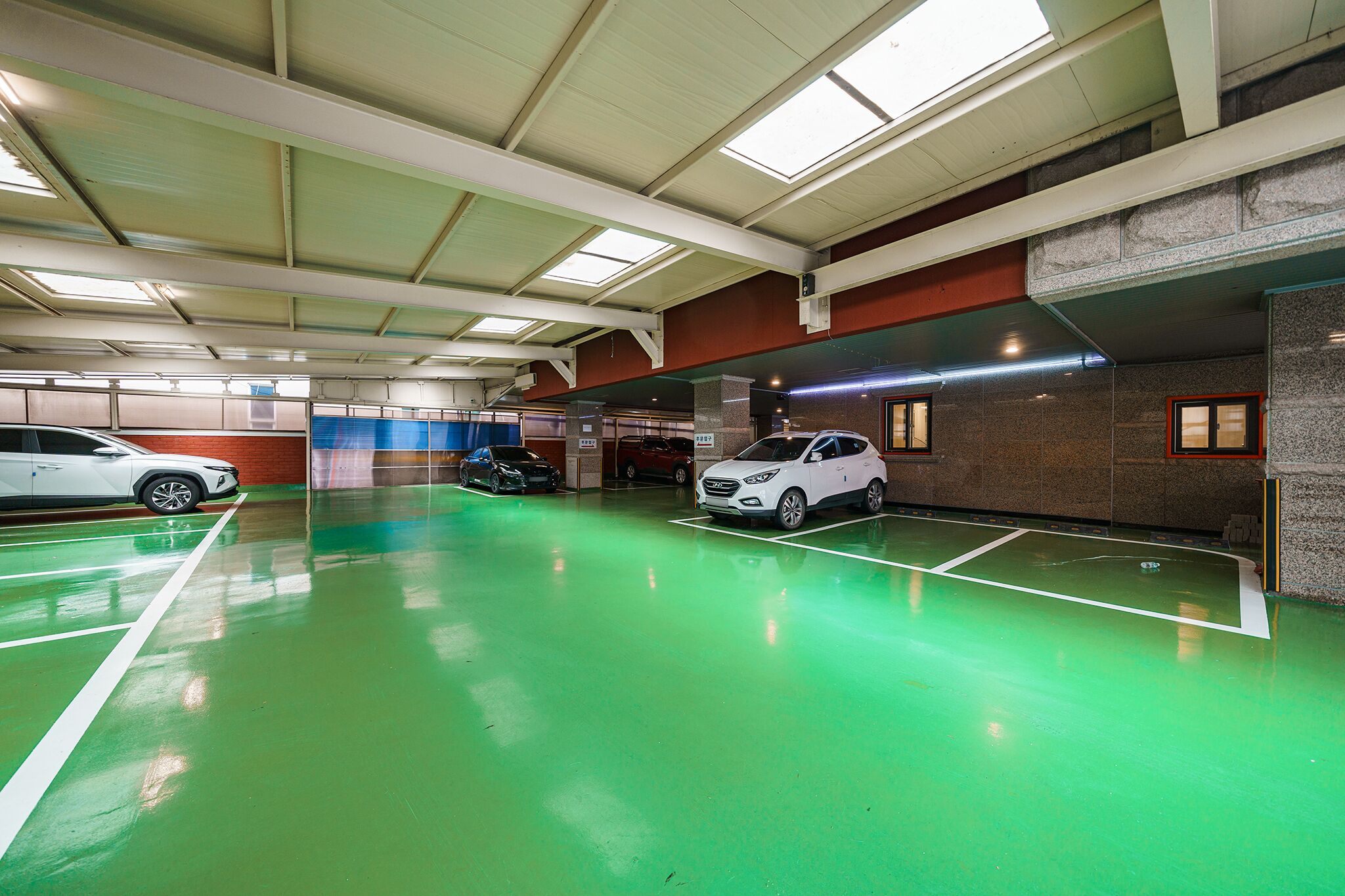 A multi-level parking garage with green flooring and white lines marking parking spaces.