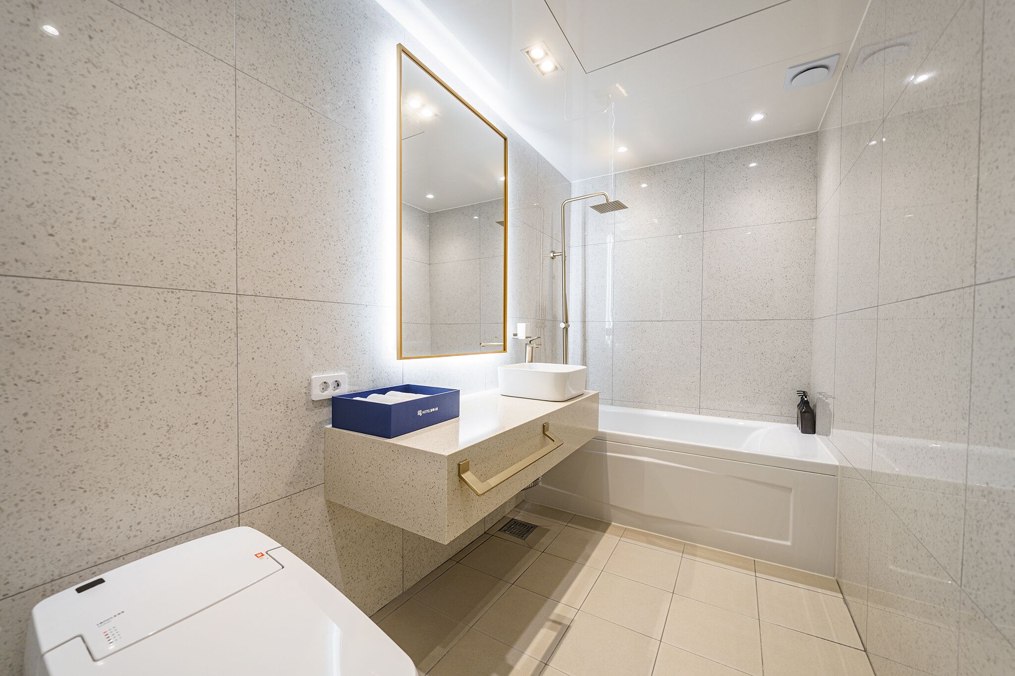 A modern bathroom with a freestanding bathtub, a large mirror, and a sink with a blue soap dish.