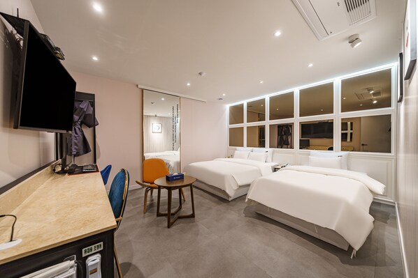A hotel room with a desk, two beds, a chair, and a TV. - Hotel Millennium (Goyang)