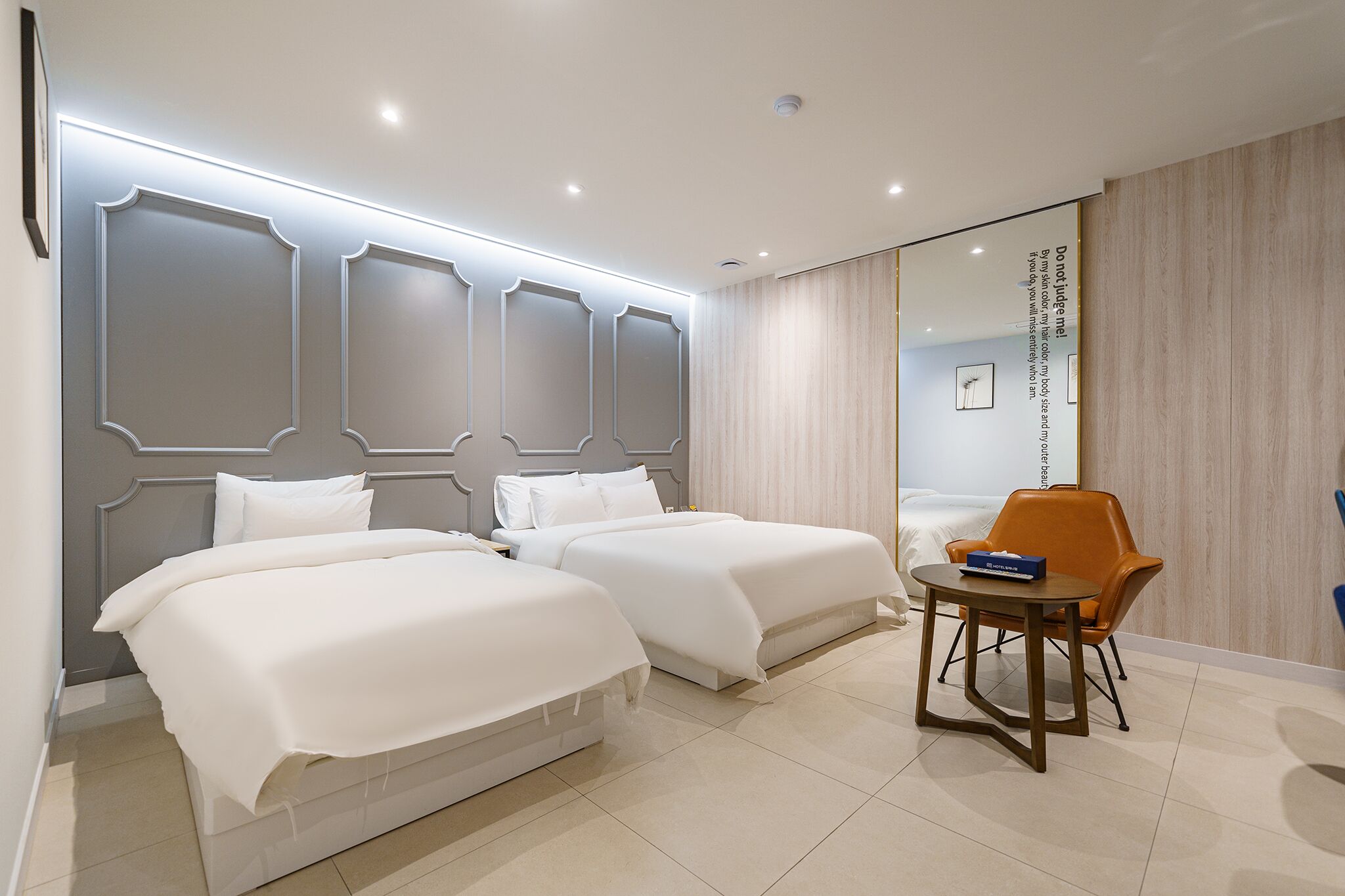 Habitación de hotel con dos camas, una mesita y una silla.