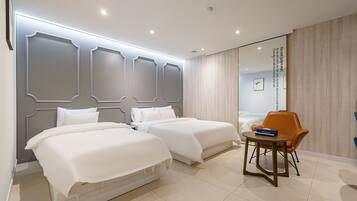 Habitación de hotel con dos camas, una mesita y una silla.
