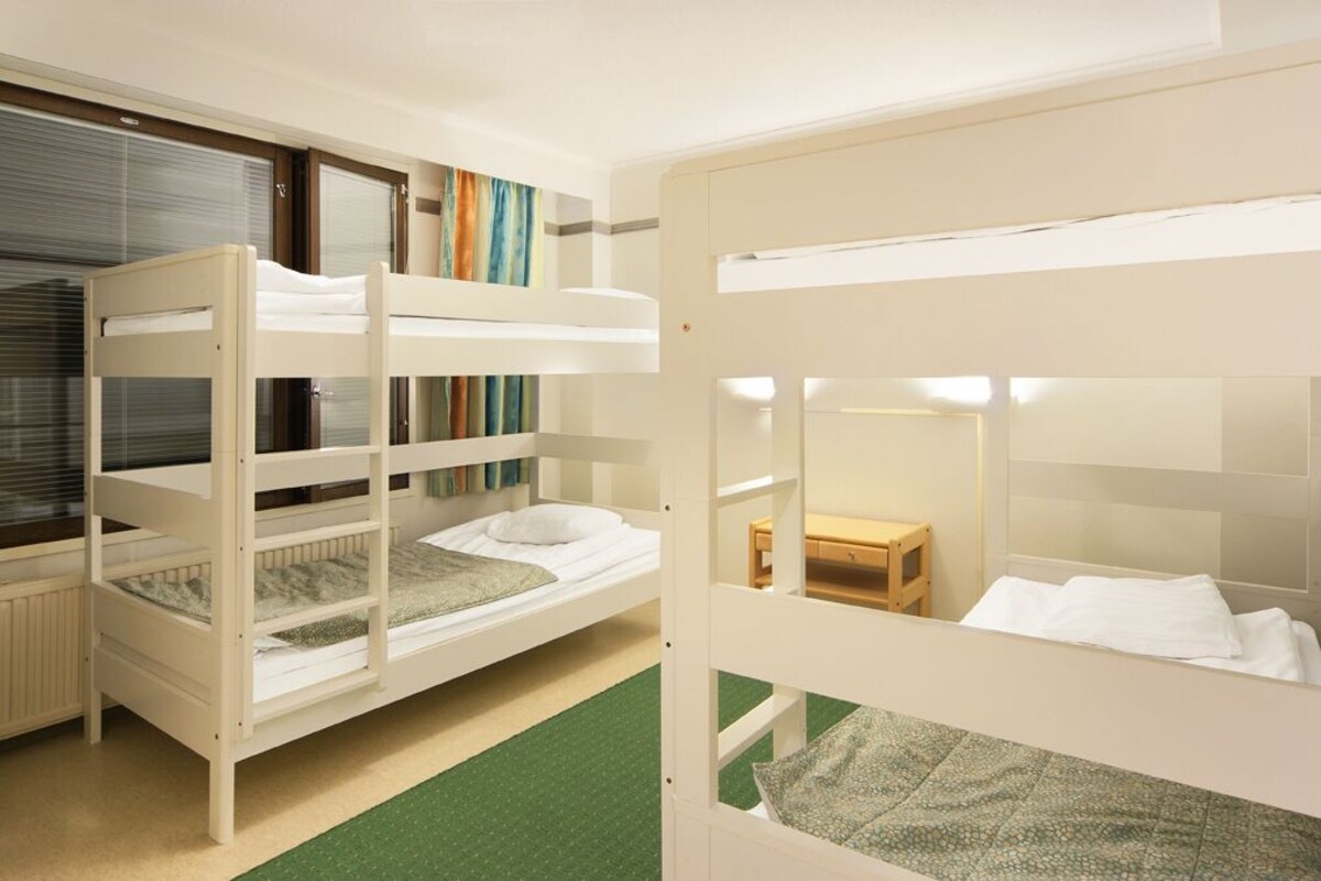 A bunk bed room with a window, a small wooden table, and a mirror.