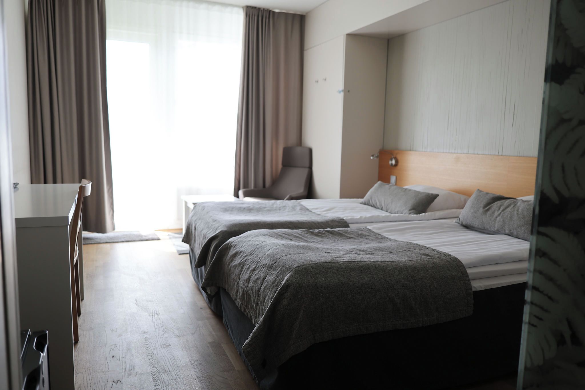 A hotel room with two beds, a desk, and a chair.