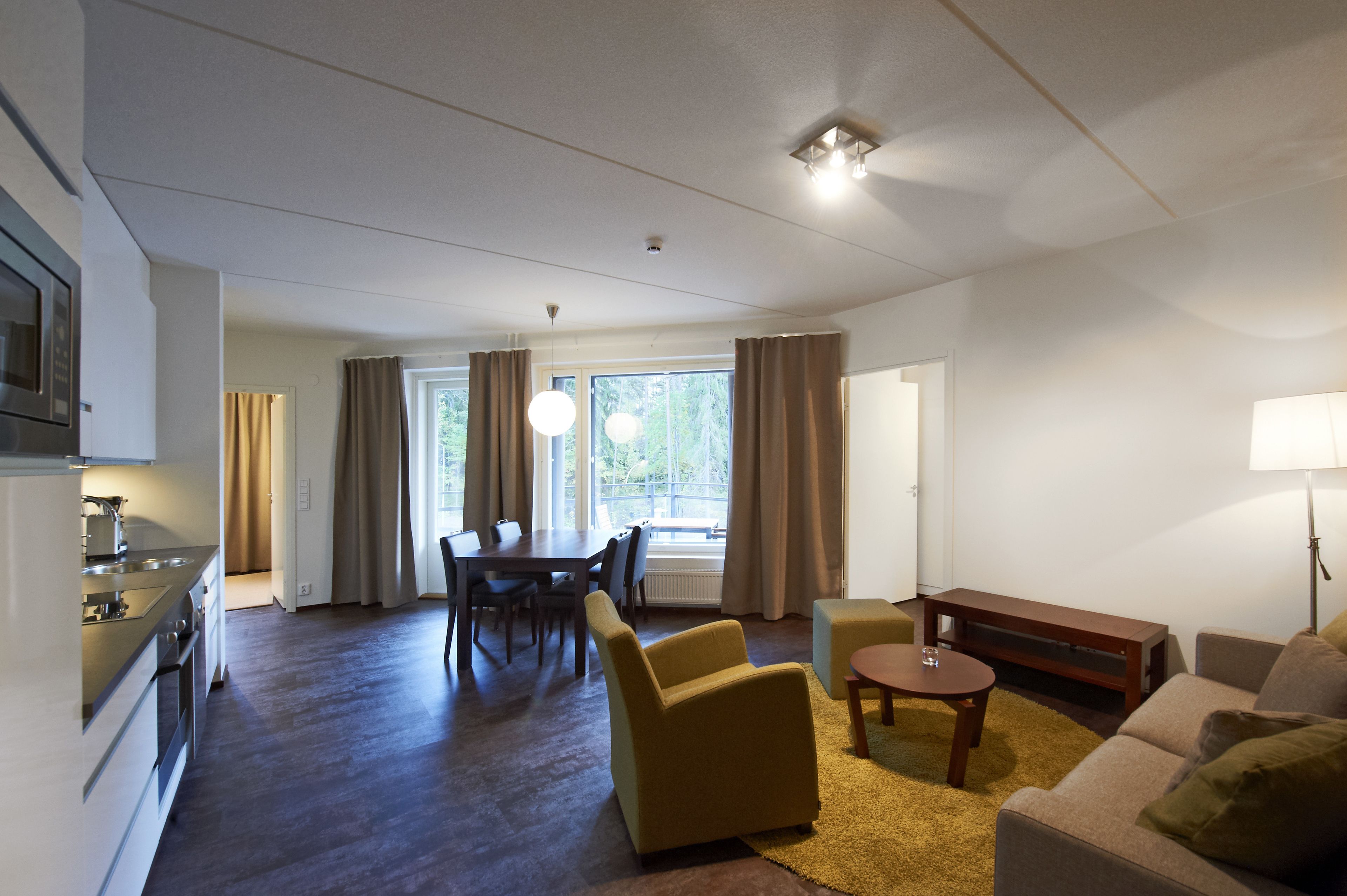 A modern living room with a dining area, a kitchen, and a large window with curtains.