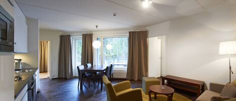 A modern living room with a dining area, a kitchen, and a large window with curtains.