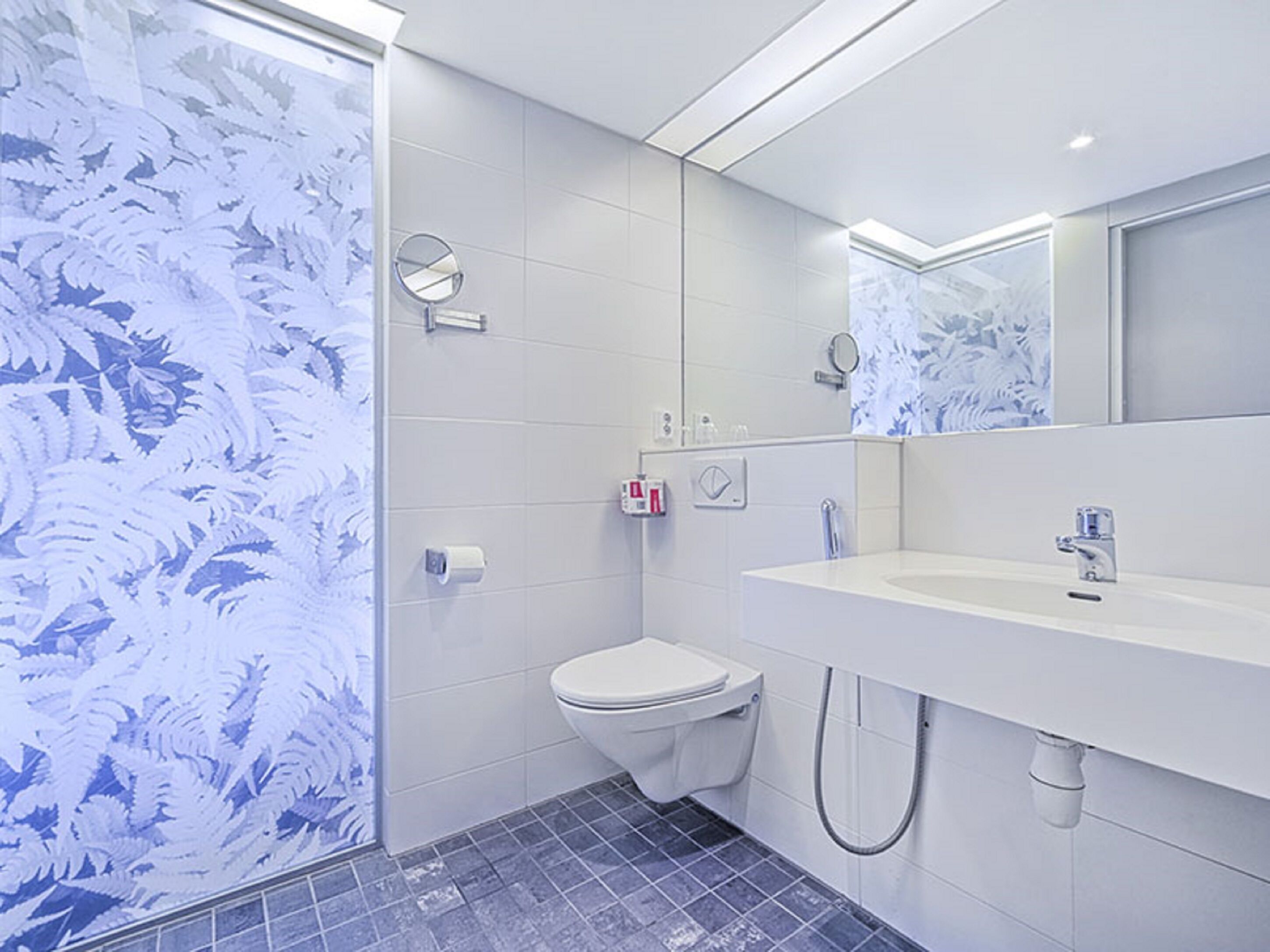 Une salle de bain moderne équipée de toilettes, d’un lavabo et d’une douche.