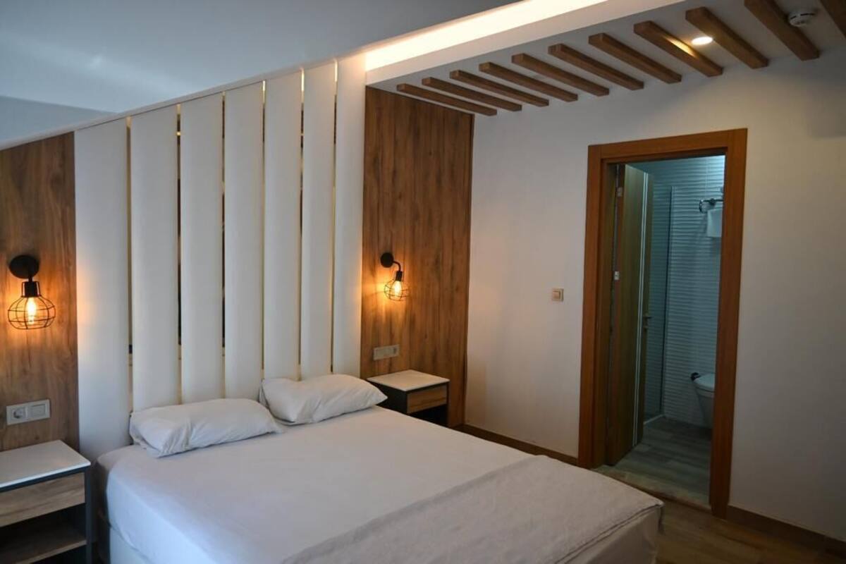Une chambre à coucher moderne avec un lit, des tables de chevet et des luminaires fixés au mur.