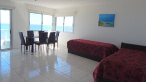 Una habitación con una mesa de comedor, sillas, una cama y un cuadro.