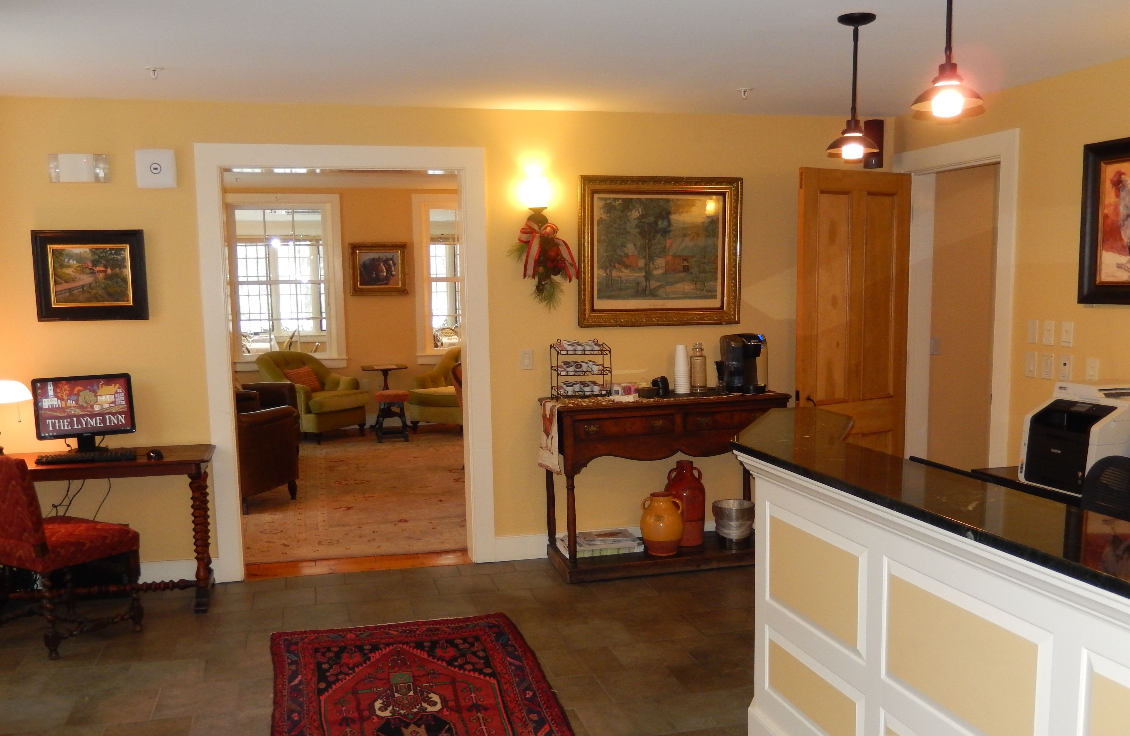 A cozy living room with a fireplace, a coffee table, and a television. There is a dining area with a table and chairs. The room has a warm color scheme and a large window.