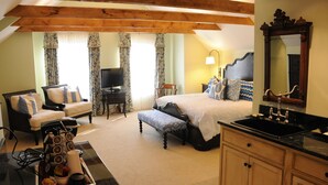 A bedroom with a bed, a sofa, a TV, a desk, and a bathroom with a sink and mirror. - The Lyme Inn (Lyme)