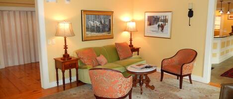 A cozy living room with a green sofa, two patterned armchairs, a coffee table, and two lamps.