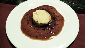 A plate with a piece of meat and a dark sauce.