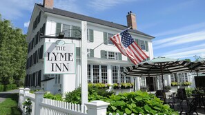 The Lyme Inn with a prominent American flag, a white picket fence, and a covered outdoor seating area.