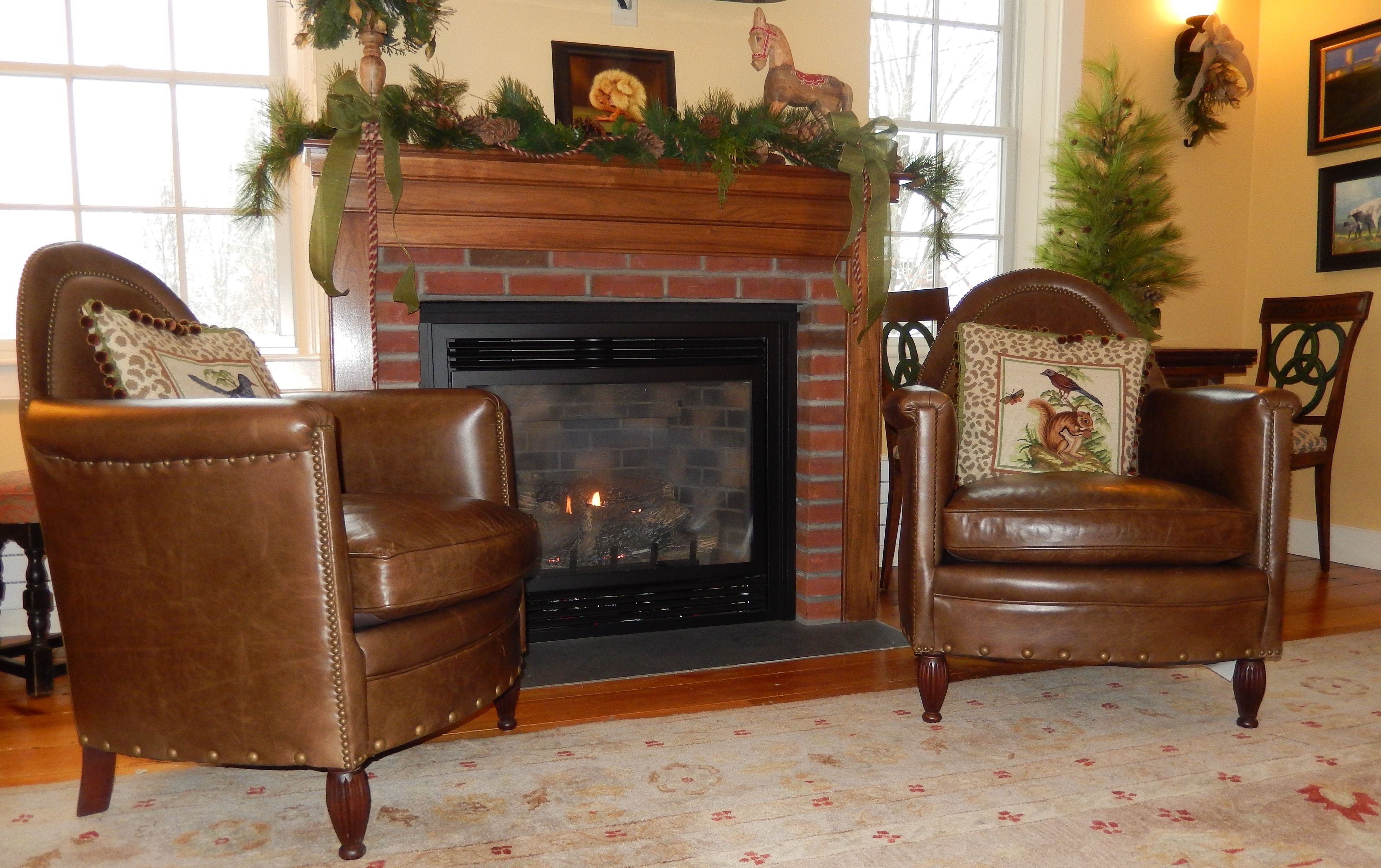A cozy living room with a fireplace, two leather armchairs, and a patterned carpet.