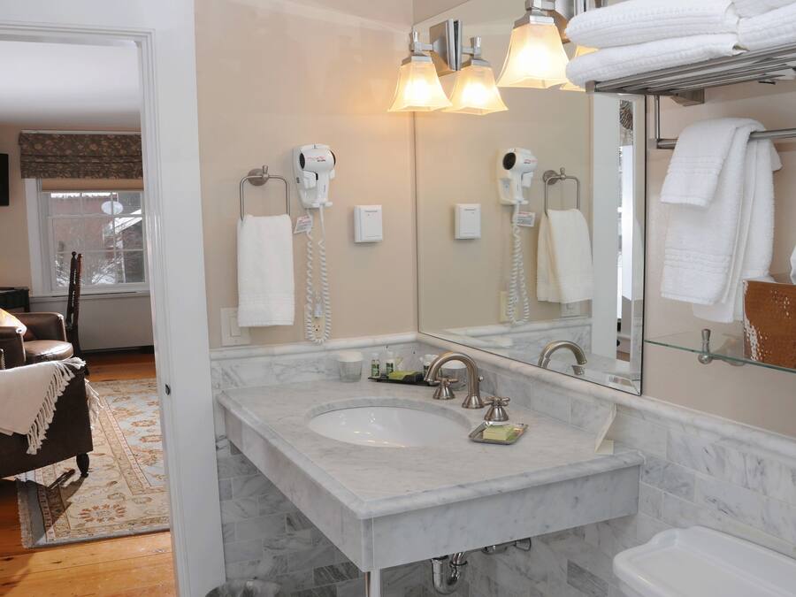 A modern bathroom with a large mirror, dual sinks, and a hairdryer.