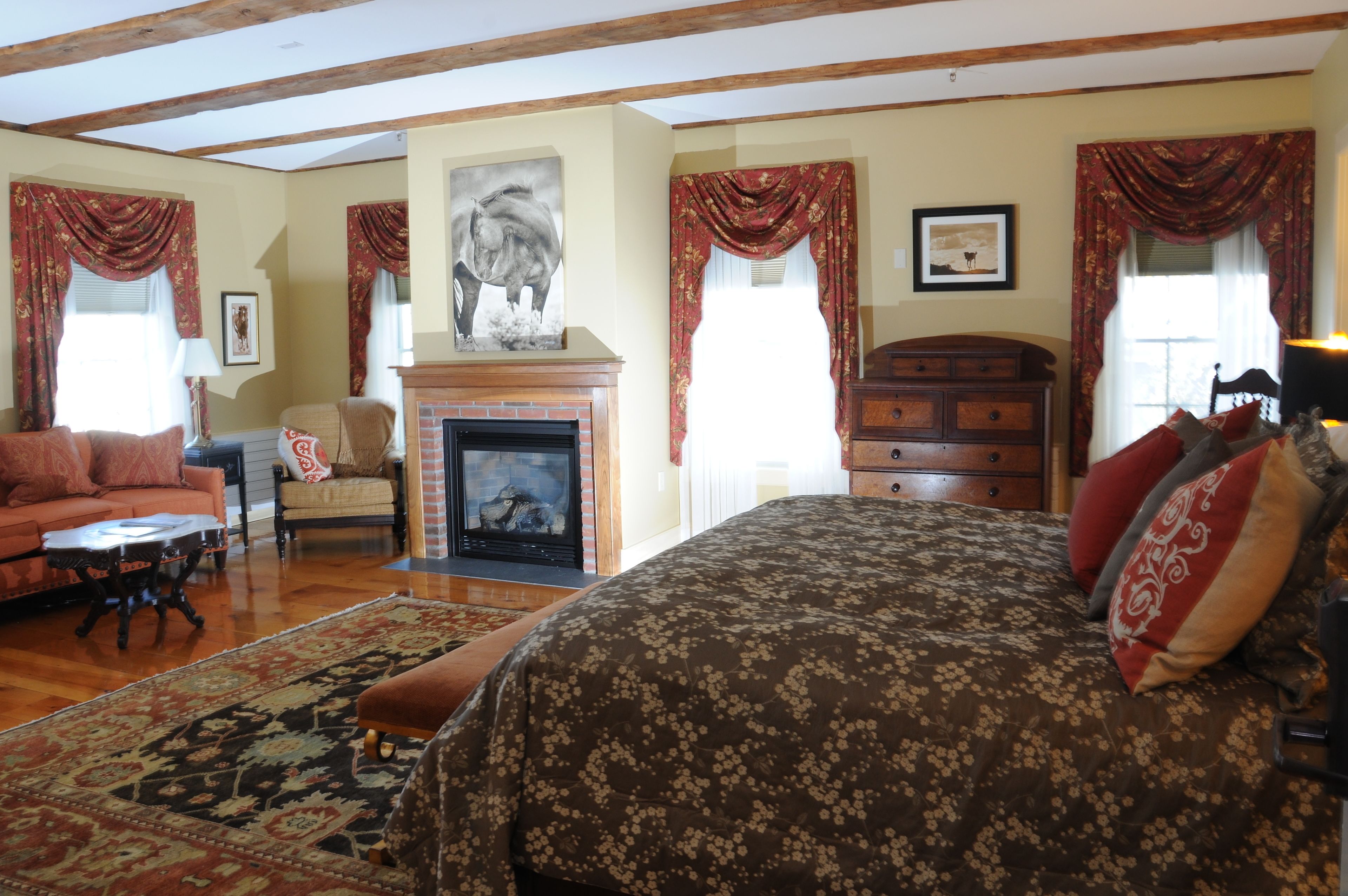 Una habitación acogedora con chimenea, una cama con ropa de cama floral, un sofá y una alfombra estampada.