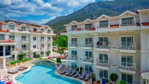Ein Hotel mit mehreren Balkonen, einem Schwimmbad und einer Bergkulisse.