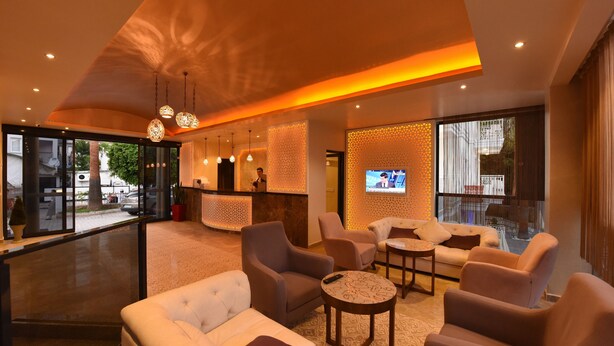 Eine moderne Hotellobby mit einer Rezeption, einer Sitzecke und einem Fernseher.