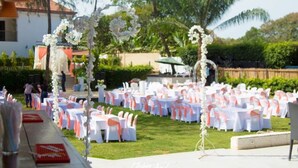 An outdoor wedding venue with rows of tables and chairs, decorated with white and orange accents. - Riviera Taouyah Hotel (Conakry)
