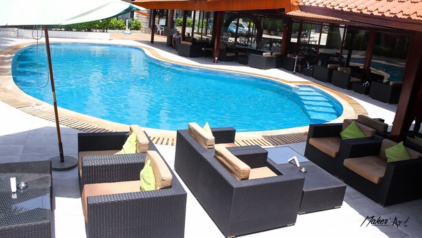 A swimming pool with lounge chairs and umbrellas, surrounded by a covered patio area. - Riviera Taouyah Hotel (Conakry)