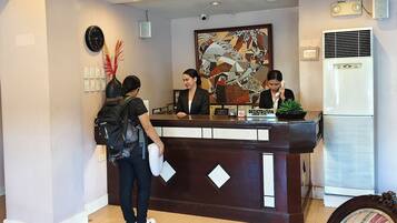 A reception desk with a clock, a framed artwork, and a registration sign.