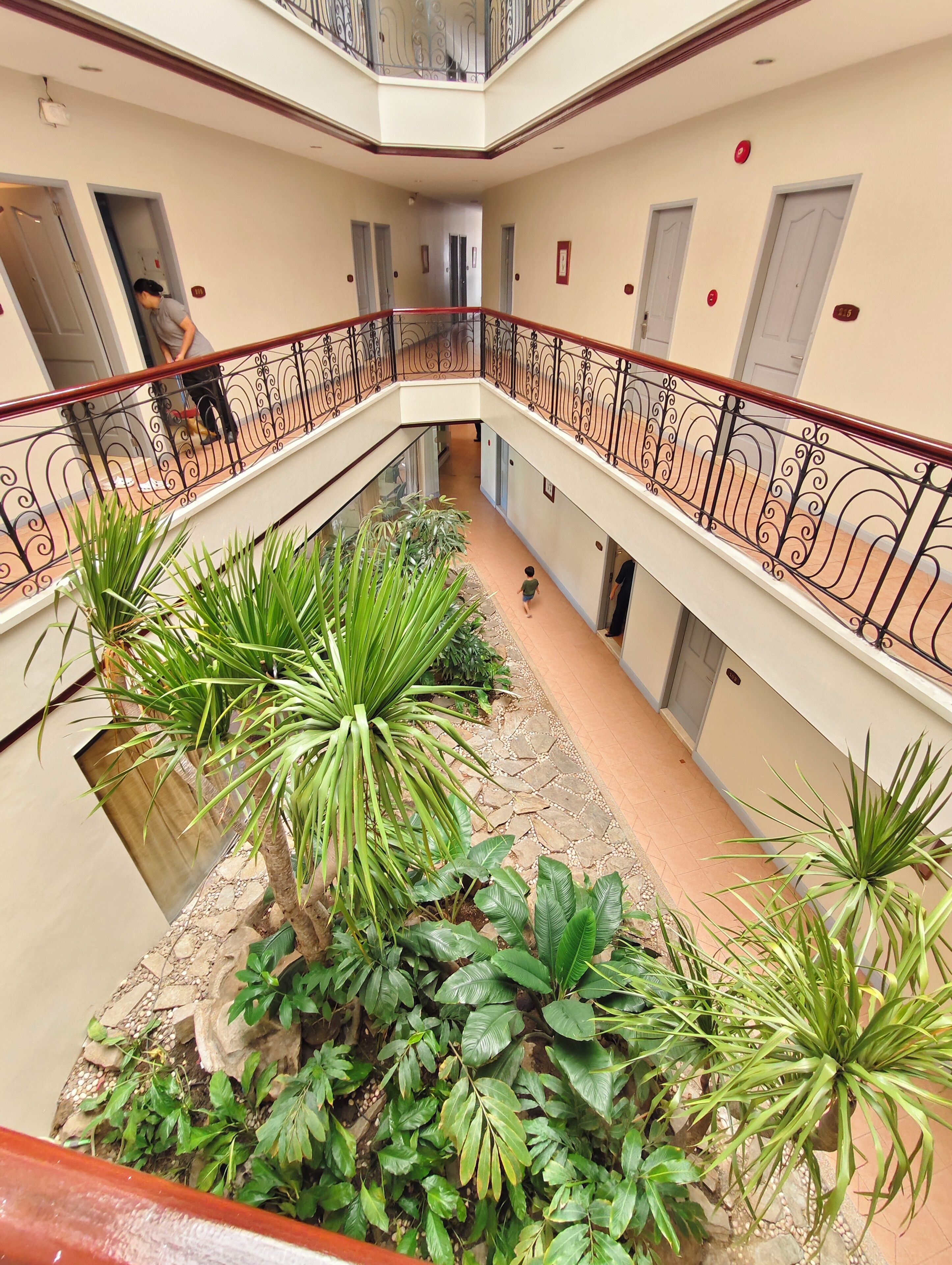 A multi-level atrium with a central garden area featuring various plants and a stone pathway.