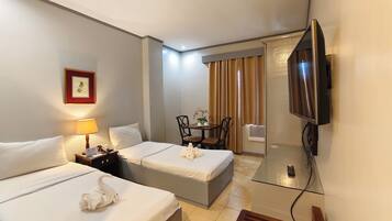 A hotel room with two beds, a desk, a chair, a television, and a picture frame on the wall.