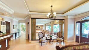 A spacious lobby with a reception desk, seating area, and a view of the dining area through a glass partition. - Casa Leticia Business Inn (Davao)