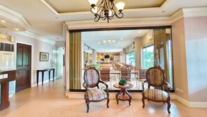 A spacious lobby with a chandelier, wooden chairs, and a view into a dining area. - Casa Leticia Business Inn (Davao)