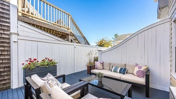 A deck with outdoor furniture, a glass-top table, and a wooden staircase. - Inn at 7 Central (Provincetown)
