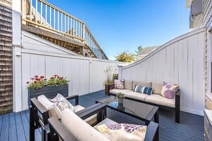 Una terraza con mobiliario exterior, una mesa de vidrio y una escalera de madera.