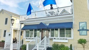 A hotel with a balcony, outdoor seating, and a sign indicating it is 'The Inn at 7 Central'. - Inn at 7 Central (Provincetown)