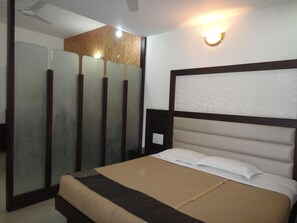 Habitación de hotel con cama, mesita de noche, lámpara de pared y espejo.