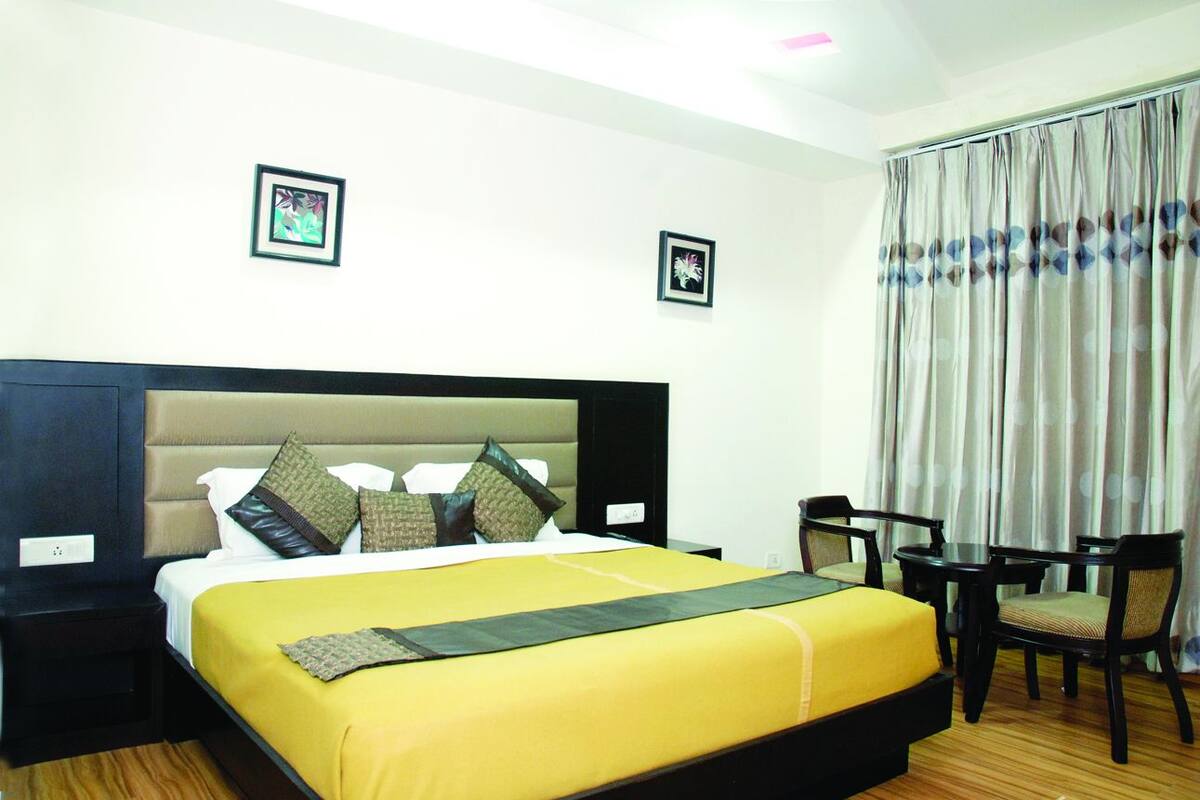 A hotel room with a bed, a nightstand, a desk, and a chair.