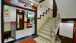 L’entrée d’un hôtel, avec une pancarte « Bienvenue », un escalier et un comptoir d’accueil.