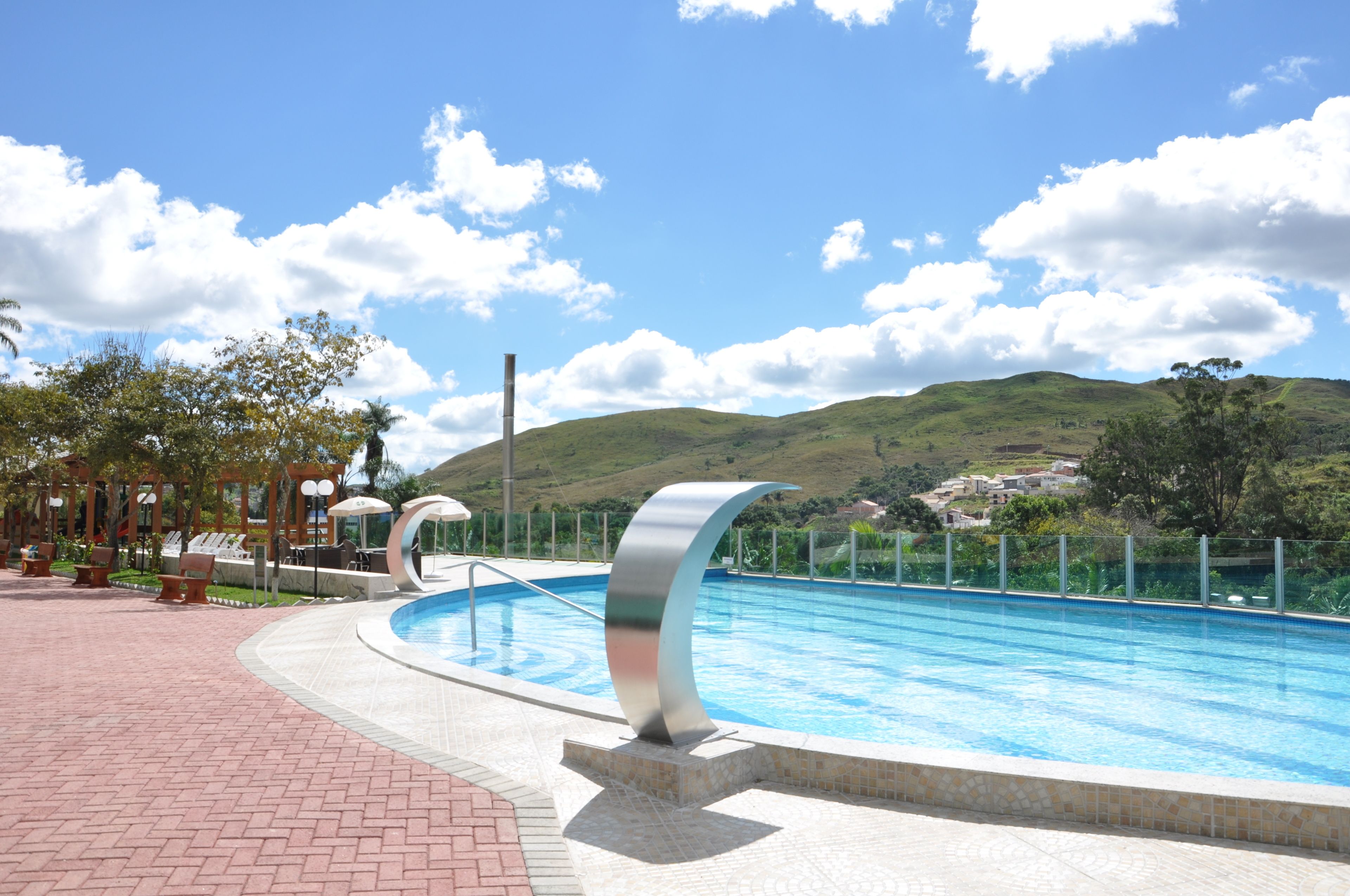 Una piscina amb disseny modern, envoltada per un passeig de maons i gandules.