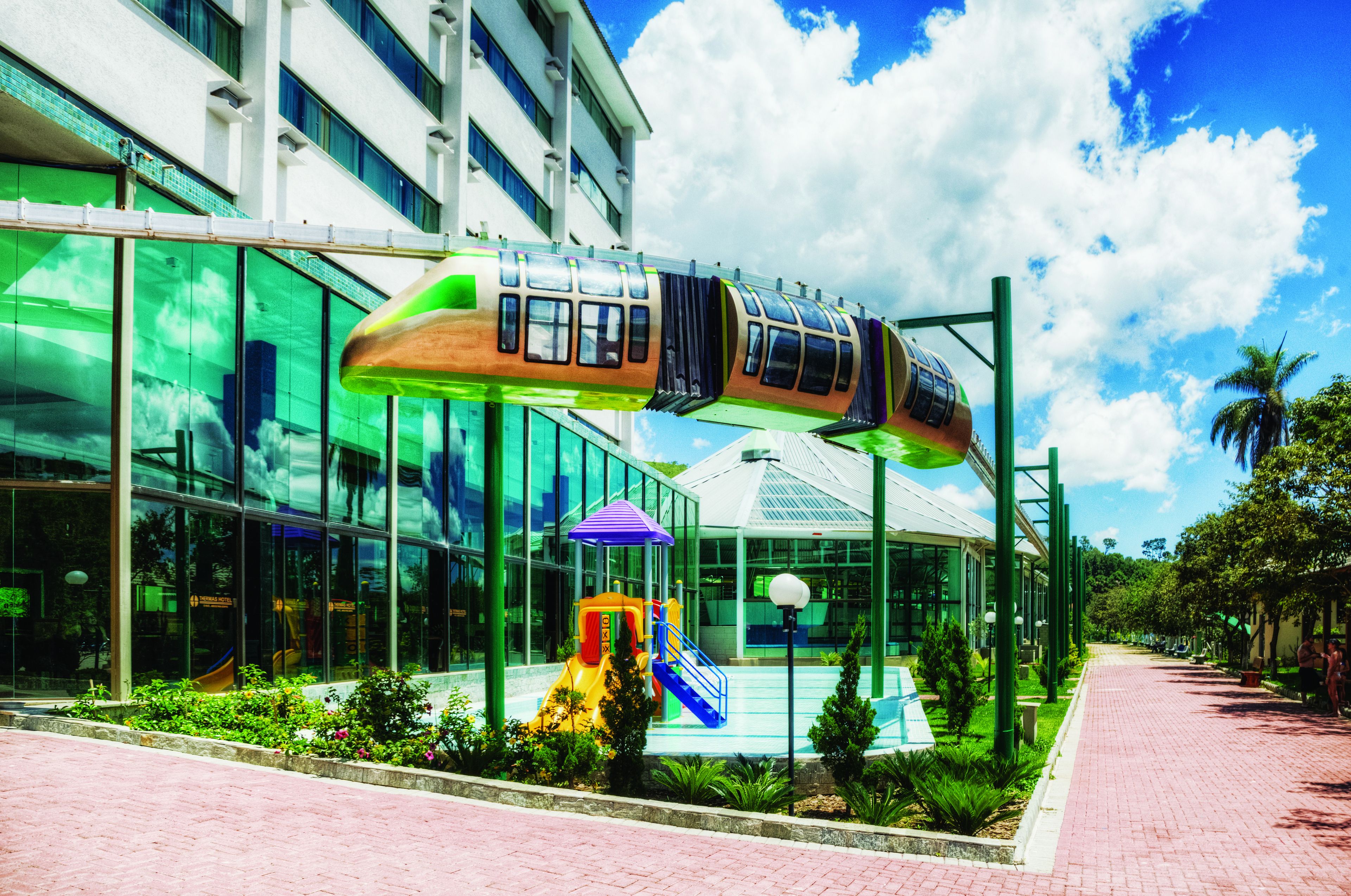 A modern building with a large glass facade, a children's play area, and a pedestrian pathway.
