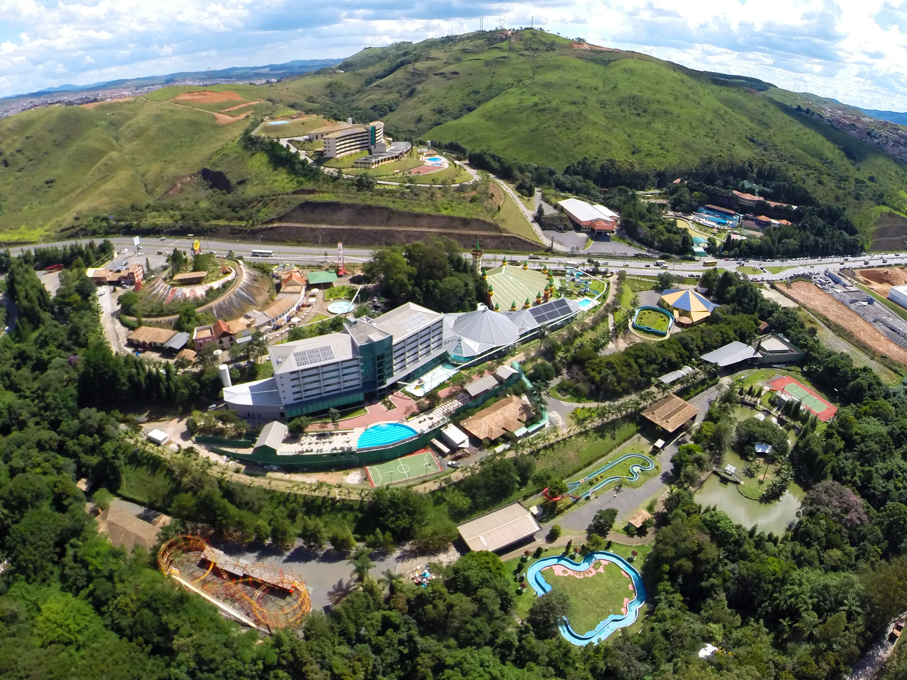 An aerial view of a resort with multiple buildings, a swimming pool, and a winding water slide.