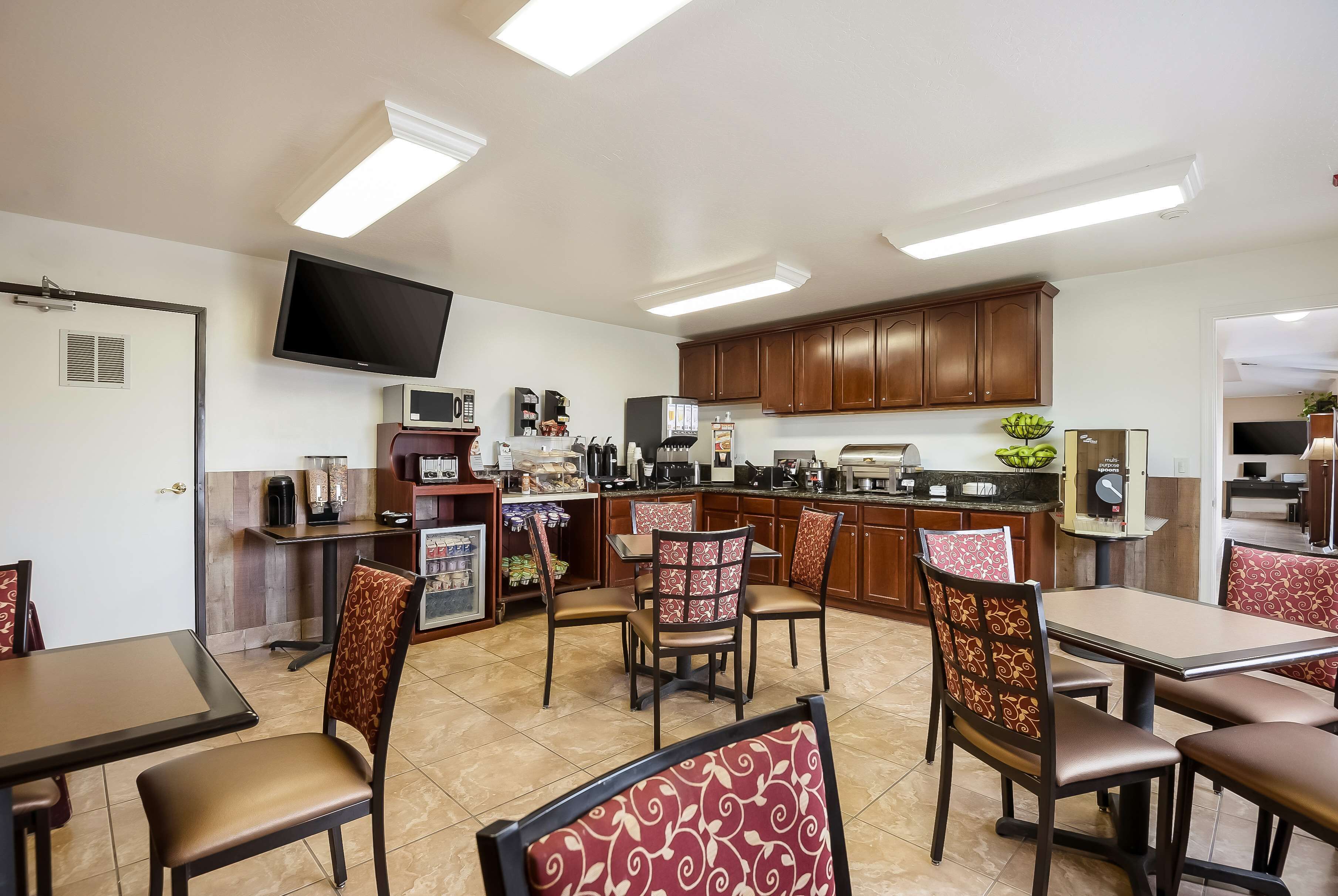 A restaurant with a kitchen area, dining tables, and chairs.