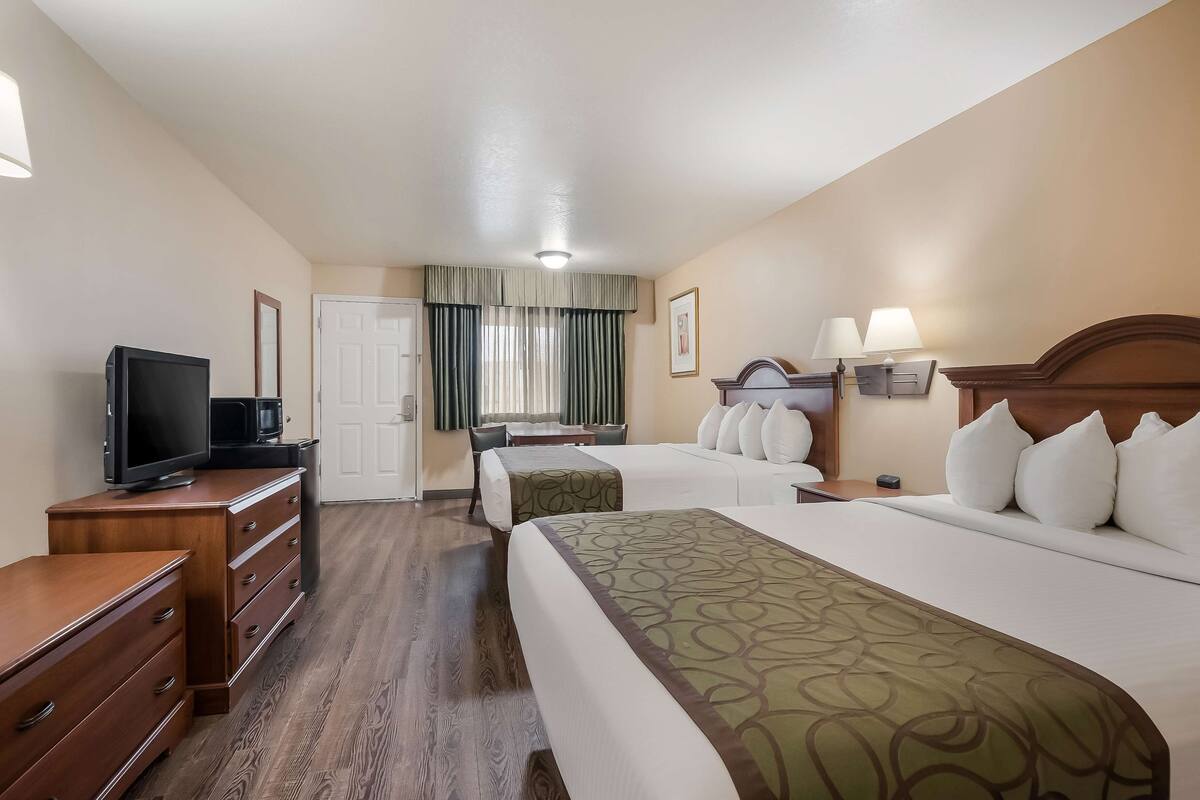 A hotel room with a bed, a desk, a television, and a dresser.