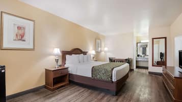 Una habitación de hotel con cama, mesitas de noche, escritorio y espejo.