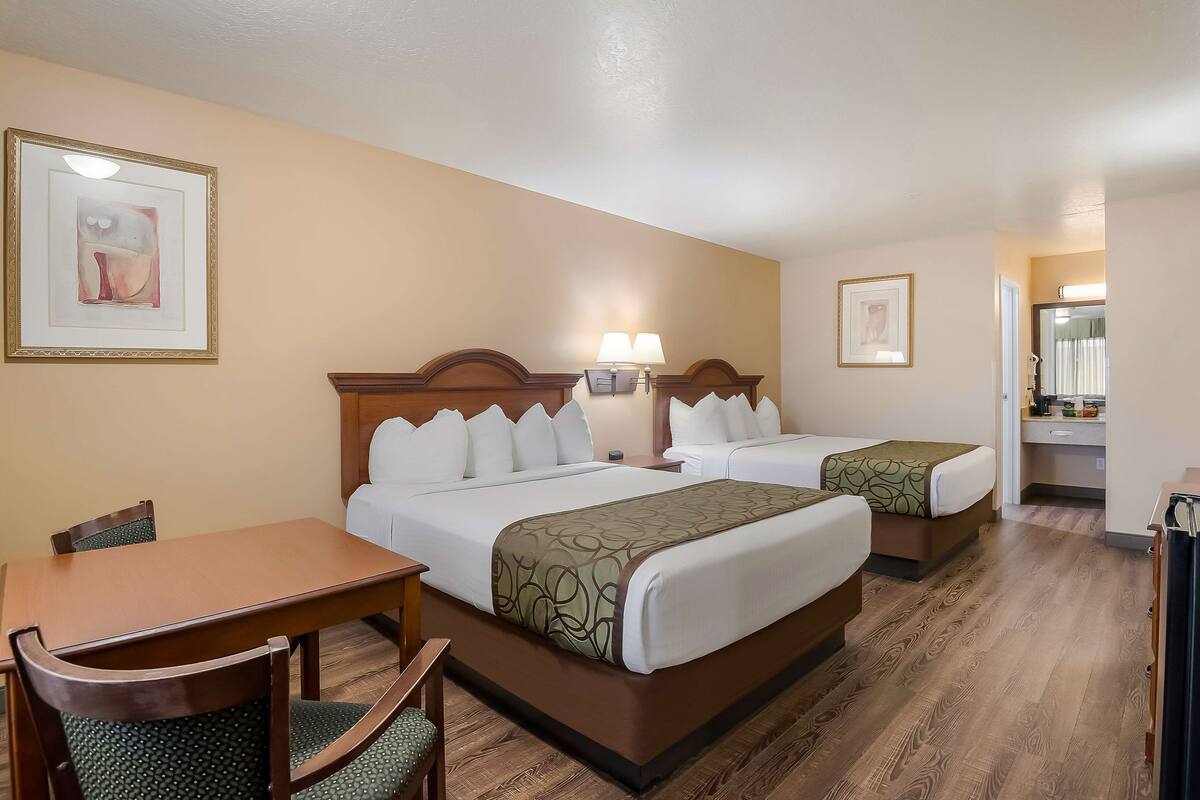 A hotel room with two beds, a dining table, and chairs.