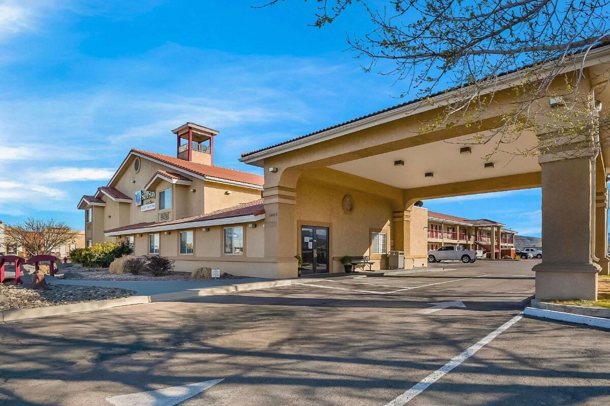 A hotel with a covered parking area, a visible entrance, and a building with a red-tiled roof.