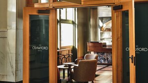A hotel lobby with a wooden reception desk, seating area, and a sign reading "The Crawford Hotel". - The Crawford Hotel (Denver)