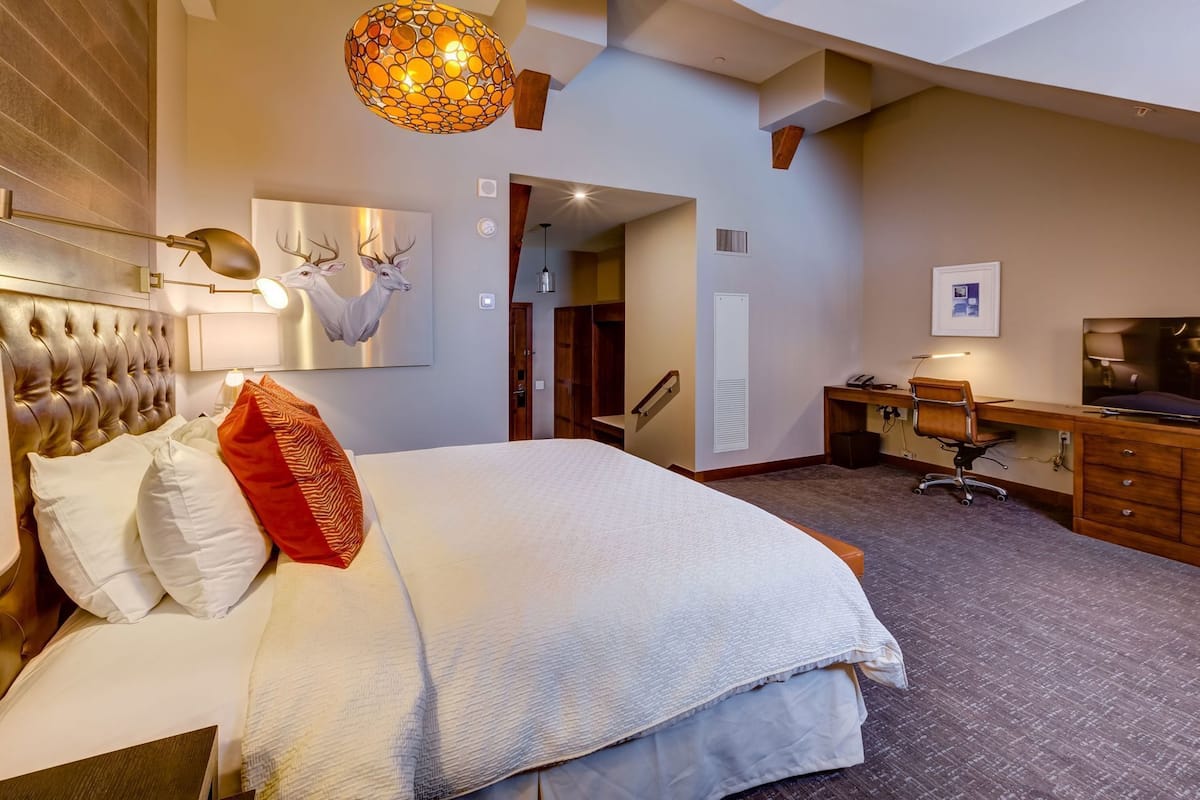 Une chambre d’hôtel dotée d’un grand lit, d’un bureau, d’une télévision et d’un luminaire au plafond original.