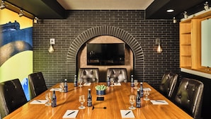 A conference room with a long wooden table, leather chairs, and a large TV screen. - The Crawford Hotel (Denver)